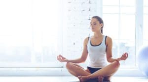 A woman sitting in the lotus position on her knees.